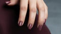 Woman hand with burgundy color nail polish on her fingernails. Burgundy nail manicure with gel polish at luxury beauty salon. Nail