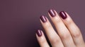 Woman hand with burgundy color nail polish on her fingernails. Burgundy nail manicure with gel polish at luxury beauty salon. Nail