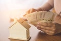 Woman hand calculating money with house model on wooden table planing to buy or rent home Royalty Free Stock Photo