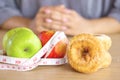 Woman hand choosing healthy or unhealthy eating between apples and donuts