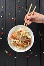 Woman hand with chopsticks reaching for Asian udon noodles with