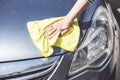 A woman hand cleaning car with microfiber cloth, car detailing or valeting concept. Selective focus