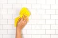 Woman hand cleaning a white subway tiles kitchen wall with a sponge cloth Royalty Free Stock Photo