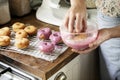 Woman hand coating fried donuts with pink frosting Royalty Free Stock Photo