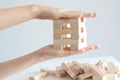 Woman hand constructing a tower of wooden blocks on a white background Royalty Free Stock Photo