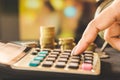 Woman hand counting expenses on calculator with stack of coins