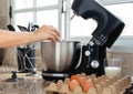 Woman hand cracking an egg inside mixer bowl for making a cake