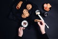 Woman hand with cup of coffee or cappuccino and chocolate cookies, biscuits on black table background. Afternoon break time. Break Royalty Free Stock Photo