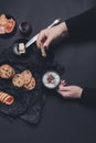 Woman hand with cup of coffee or cappuccino and chocolate cookies, biscuits on black table background. Afternoon break time. Break Royalty Free Stock Photo