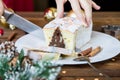 Woman hand cut christmas chocolate cake with holiday decoration. Food xmas background. Royalty Free Stock Photo