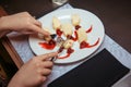 A woman hand cuts dessert with pancakes and cherries