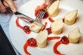 A woman hand cuts dessert with pancakes and cherries