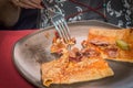 Woman hand cutting of a portion of delicious crepe with meat served on a grey plate.