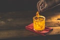 Woman hand decorate orange twist alcoholic cocktail negroni on old wooden board. Drink with gin, campari martini rosso and orange Royalty Free Stock Photo