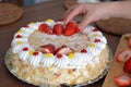 Woman hand is decorating a cream cake with strawberries Royalty Free Stock Photo