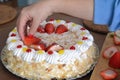 Woman hand is decorating a cream cake with strawberries Royalty Free Stock Photo