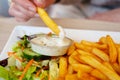 Woman hand dipping delicious French fries into mayonnaise sauce, cheese sauce.