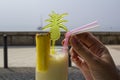 Woman hand drinking a pineapple smoothie cocktail at the beach Royalty Free Stock Photo