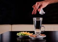 Woman hand dropping tea bag in hot water glass Royalty Free Stock Photo