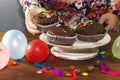 Woman hand eating chocolate arabic homemade cupcake, madeleine with colorful ballons and smarties. birthday party Royalty Free Stock Photo