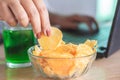 Woman hand eating fast food potato chips with soda glass at office desk Royalty Free Stock Photo