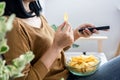 Woman hand eating potato chips and holding remote tv watching series sitting on sofa