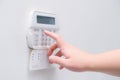 Woman hand entering alarm system password of an apartment, house of business office. Surveillance and protection console against