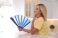 Woman with hand fan suffering from heat at home. Summer season Royalty Free Stock Photo