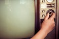 Woman hand fine tuning vintage television with control button.