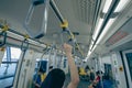 Woman hand firm grip safety handrail in elevated monorail train. Mass transit system in modern city. Inside of electric train.