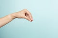 Woman hand gesture. Female hand holding some like object or blank card on light blue background Royalty Free Stock Photo