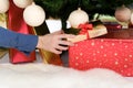 Woman hand is giving gift under christmas tree