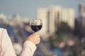 Woman hand with glass of wine against the background of town