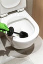 Woman hand in glove cleaning wc bowl with brush at restroom