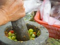 Woman hand is grinding chili and tomatoes by granite mortar Royalty Free Stock Photo