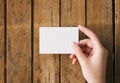 Woman hand hold blank white business card mockup on a wooden table. Branding design template concept Royalty Free Stock Photo