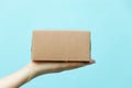 Woman hand hold brown corrugated box on blue wall background with copy space Royalty Free Stock Photo