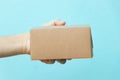 Woman hand hold brown corrugated box on blue wall background with copy space Royalty Free Stock Photo