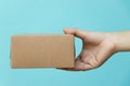 Woman hand hold brown corrugated box on blue  wall background with copy space Royalty Free Stock Photo