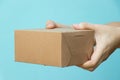 Woman hand hold brown corrugated box on blue  wall background with copy space Royalty Free Stock Photo