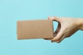 Woman hand hold brown corrugated box on blue  wall background with copy space Royalty Free Stock Photo