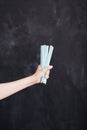 Woman hand hold cocktail straw blue on black background