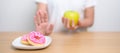 woman hand hold green Apple and reject donut, female fitness choose between fruit is Healthy and sweet is Unhealthy junk food. Royalty Free Stock Photo