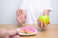 woman hand hold green Apple and reject donut, female fitness choose between fruit is Healthy and sweet is Unhealthy junk food. Royalty Free Stock Photo