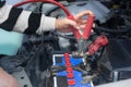 Woman hand hold jumper cables to car battery Royalty Free Stock Photo