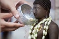 Woman hand hold little bowl to bath Buddha statue Royalty Free Stock Photo
