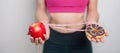 woman hand hold red Apple and donut, female fitness choose between fruit is Healthy and sweet is Unhealthy junk food. Dieting Royalty Free Stock Photo