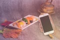 Woman hand hold smart phone on blurred japanese sushi set Royalty Free Stock Photo