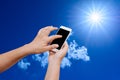 Woman hand hold and touch screen smart phone on blue sky background Royalty Free Stock Photo