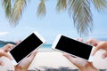 Woman hand hold and touch screen smart phone over blurred beautiful blue sky with palm tree on the beach background. Royalty Free Stock Photo